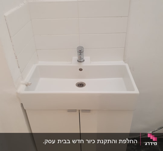 כיור לבן עם ברז כרום מותקן על ארון